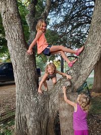 Sisters playing while climbing on tree