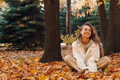 Portrait of smiling young woman sitting in forest