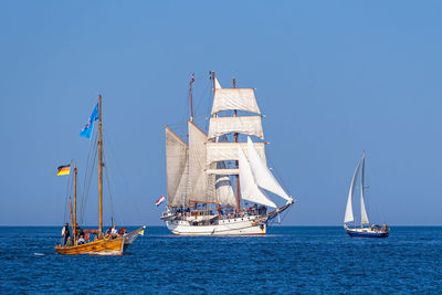 Sailboat sailing on sea against clear blue sky