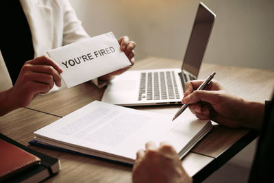 Midsection of person holding paper with text on table