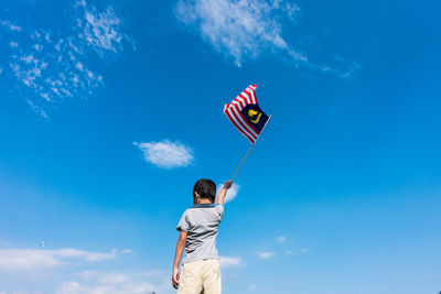 Low angle view of child playing against blue sky