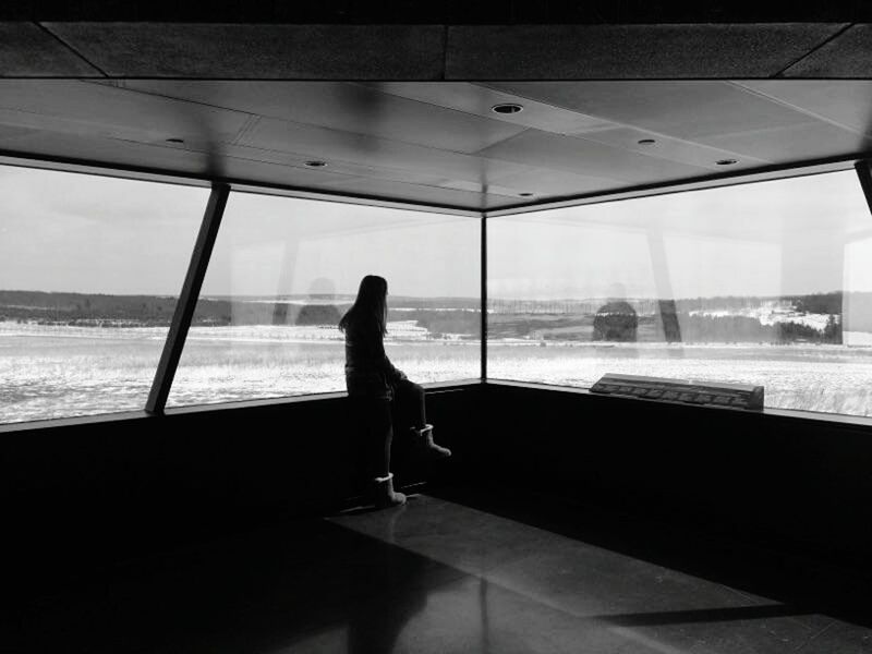 WOMAN LOOKING THROUGH WINDOW AT AIRPORT