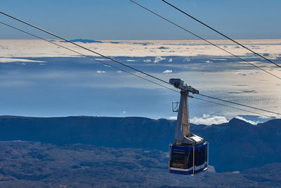 Overhead cable car on snowcapped mountains against sky