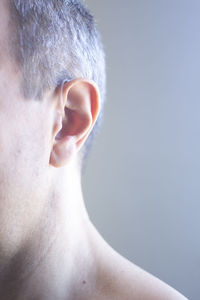 Close-up man wearing hearing aid against wall