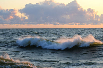 Scenic view of wave in sea against sky during sunset