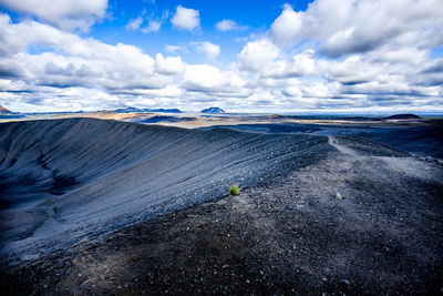 Lava rocks on stretch of sand with cloudy blue sky at lake mivatn near husavik in iceland