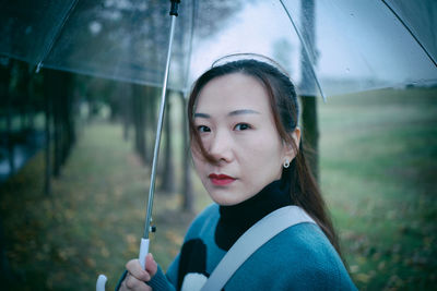 Portrait of mid adult woman holding umbrella in park