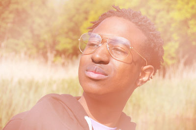 Portrait of smiling young woman wearing sunglasses on field