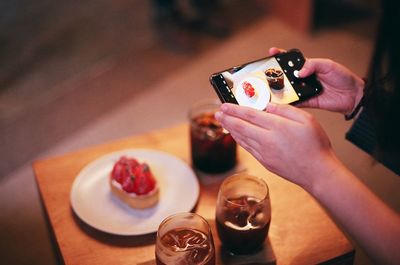 Cropped hand photographing coffee cup on table