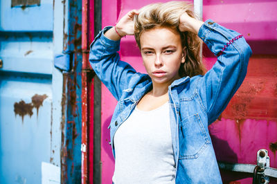 Young woman wearing denim jacket against metal structure