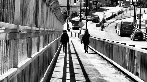 Rear view of man walking on footpath in city
