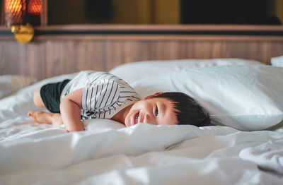 Portrait of smiling boy lying on bed