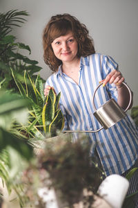 Portrait of young woman standing by plants