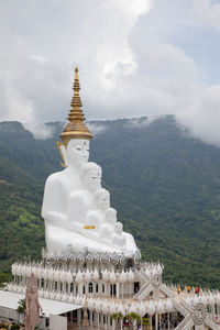 Temple against building and mountains against sky