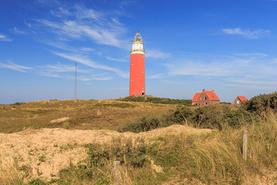 Lighthouse on field against sky