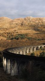 Arch bridge over landscape against sky
