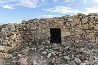 Stone wall of old building against sky