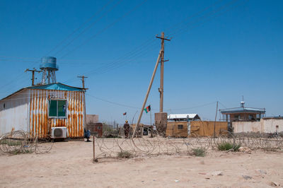 Houses on field against clear blue sky