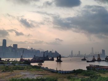 Scenic view of city by river against sky