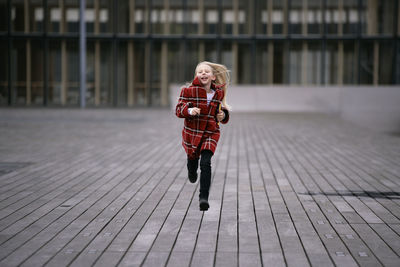 Full length of girl running on wooden floor