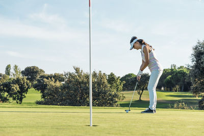 Full length of woman playing at golf course