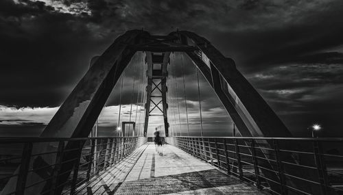 View of footbridge against cloudy sky