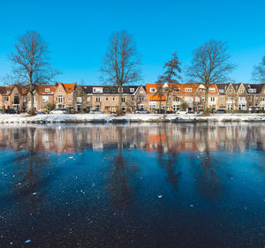 Canal by buildings against blue sky