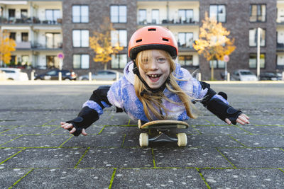Happy elementary girl lying on skateboard