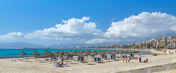 Panoramic view of people on beach against sky