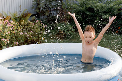 Cheerful five-year-old kid plays in the pool. funny boy splashes in an inflatable pool with 