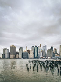 Modern buildings by river against sky in city new york city