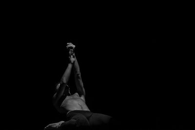 Shirtless man bending against black background