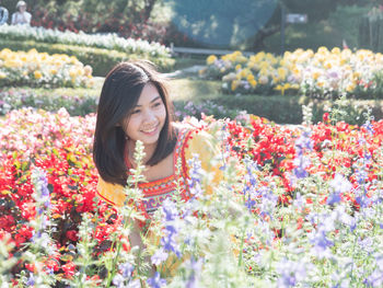 Smiling young woman looking at flowers in park