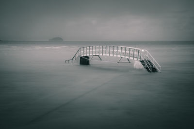 Footbridge over river against sky