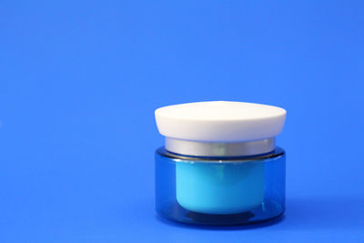 Close-up of glass of jar on table against blue background