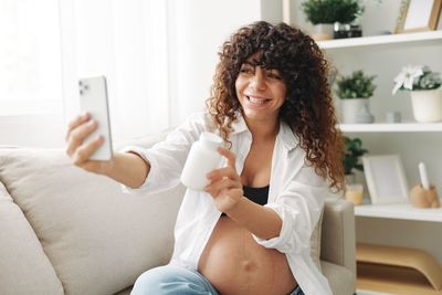 Young woman using mobile phone while sitting on sofa at home