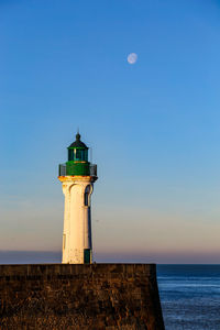 Lighthouse by sea against sky