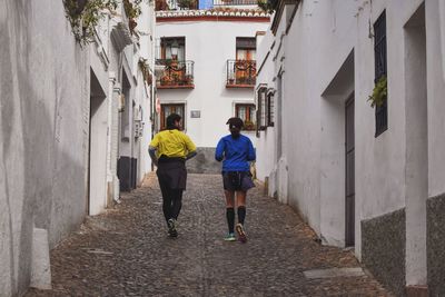 Rear view full length of friends jogging on alley