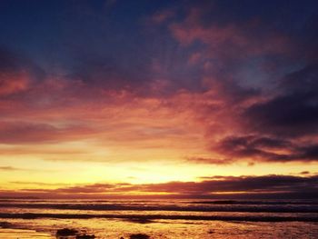 Scenic view of sea against dramatic sky during sunset