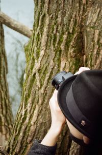 Man photographing on tree trunk against sky