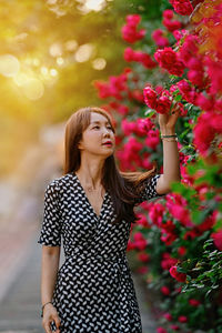 Beautiful young woman standing by flowering plants