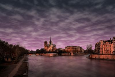 View of buildings at waterfront against cloudy sky