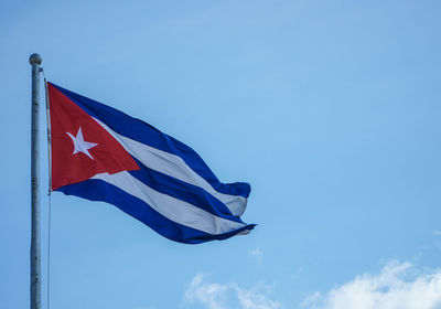 Low angle view of cuban flag against blue sky