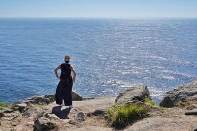 Rear view of man standing on rock by sea