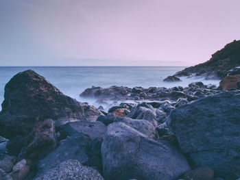 Scenic view of rocks on beach against sky