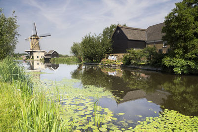 House by lake against sky