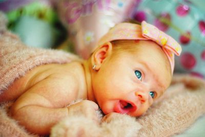 Close-up of cute baby girl lying on bed at home