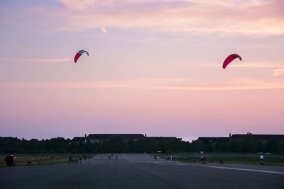 People paragliding against sky during sunset