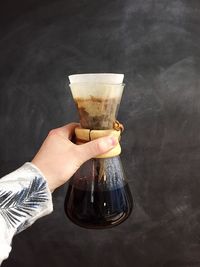 Cropped image of hand holding filter coffee pot against wall