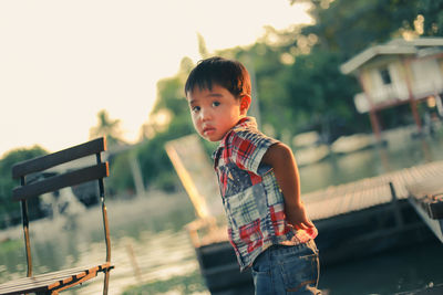 Portrait of boy standing against lake during sunset
